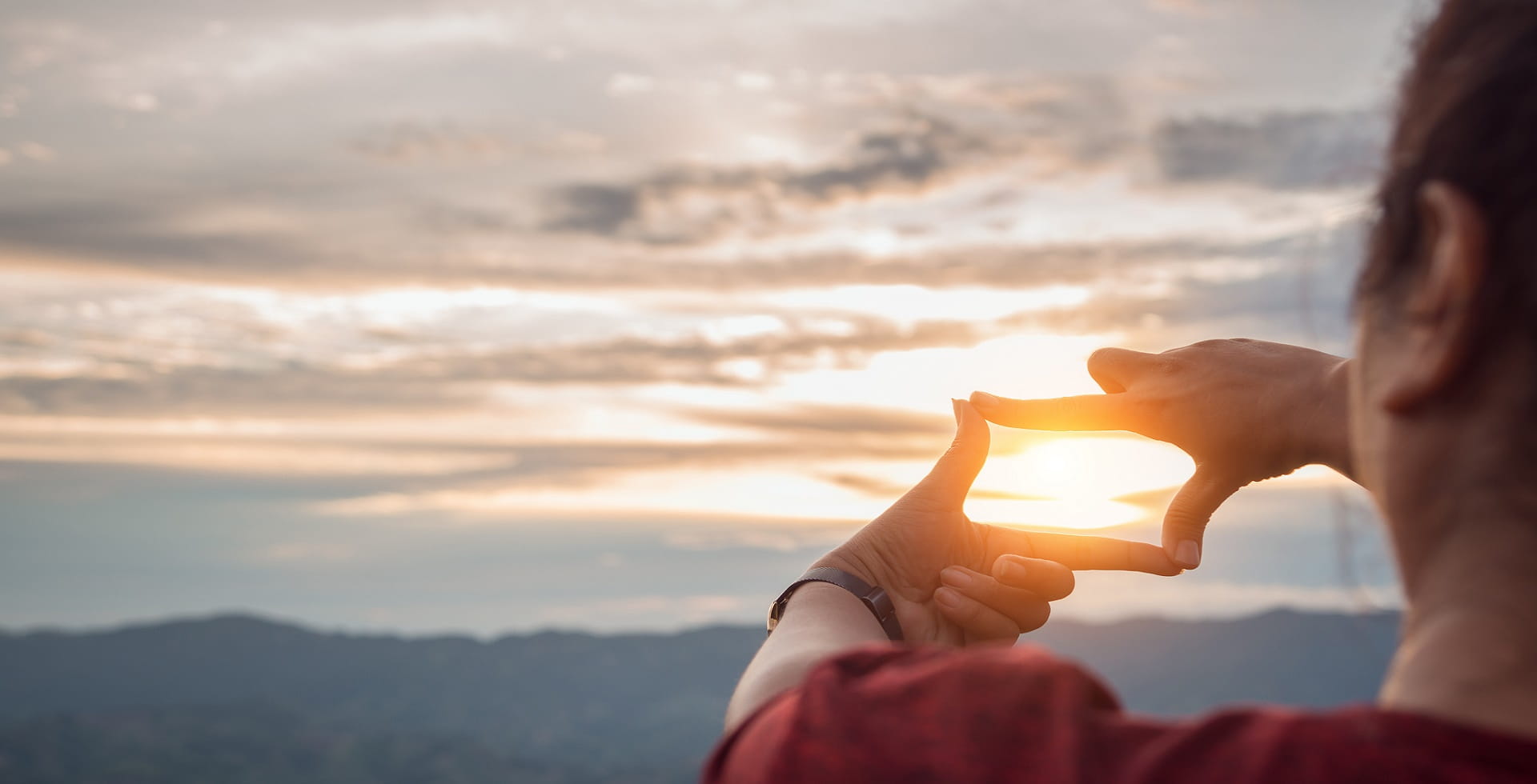 The woman making frame round the sun with her hands in sunrise
